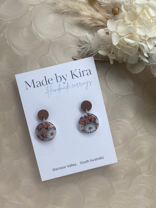 Pair of earrings on a 'Made by Kira' card with decorative flowers in the background